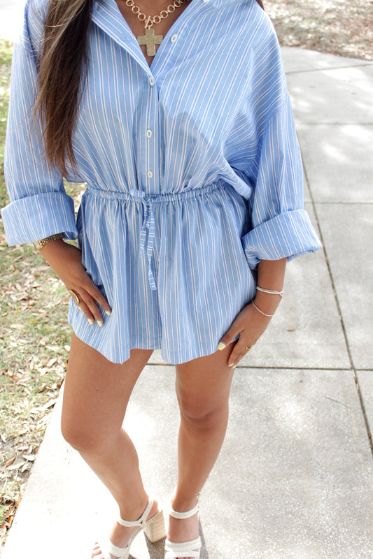 Person wearing a blue striped romper standing on a stone surface.
