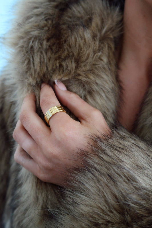 Hand with a gold ring on a fur surface