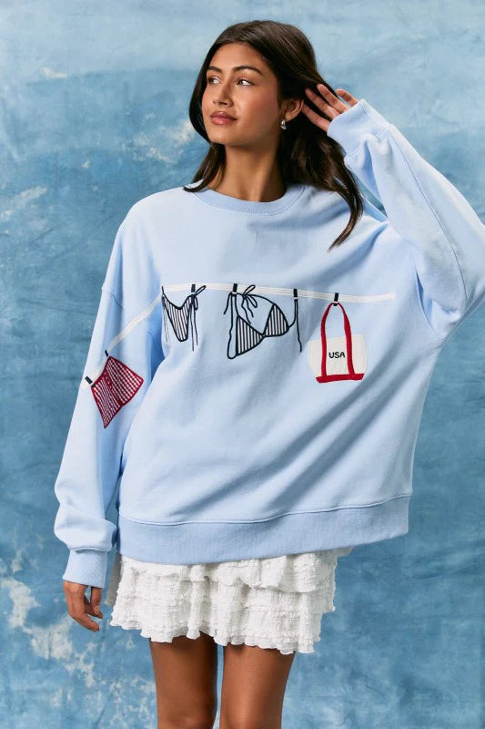 Woman wearing a light blue sweatshirt with graphic designs against a textured blue background