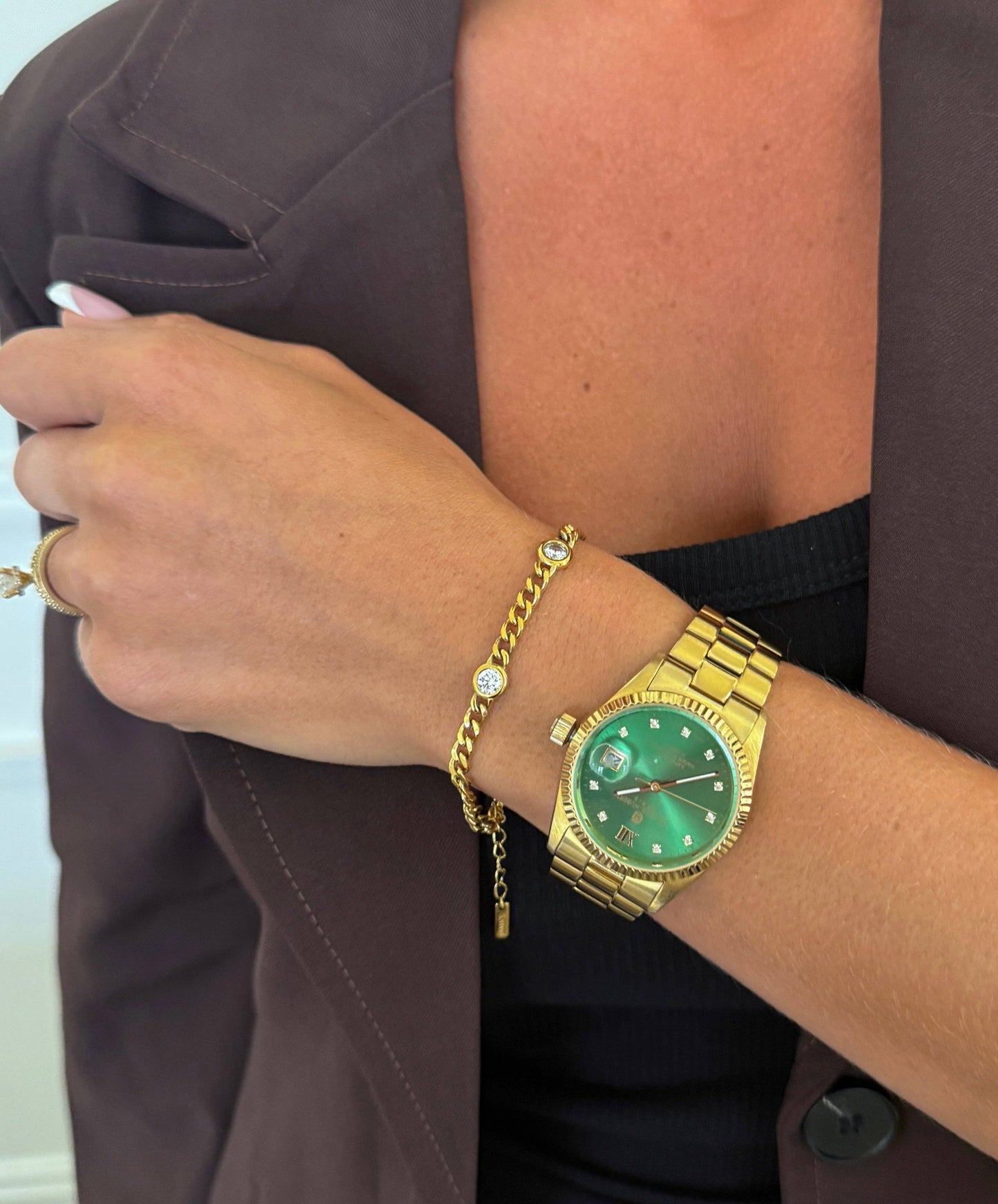 Gold watch and bracelet on a wrist with a blurred background