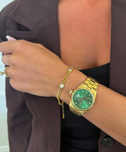 Gold watch and bracelet on a wrist with a blurred background